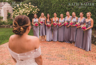 bride looking at bridesmaids in grey dresses